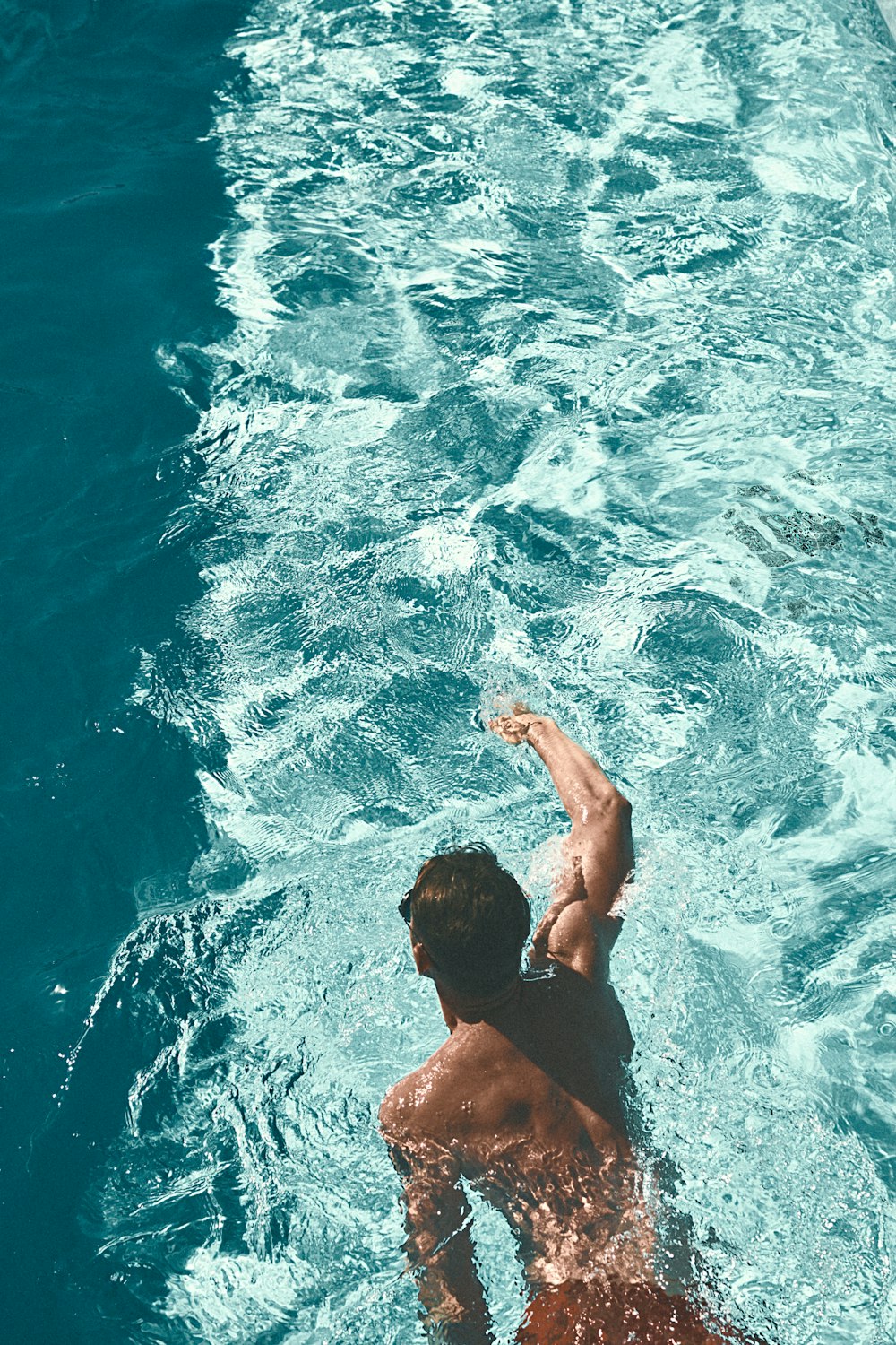 a man swimming in a pool with a frisbee