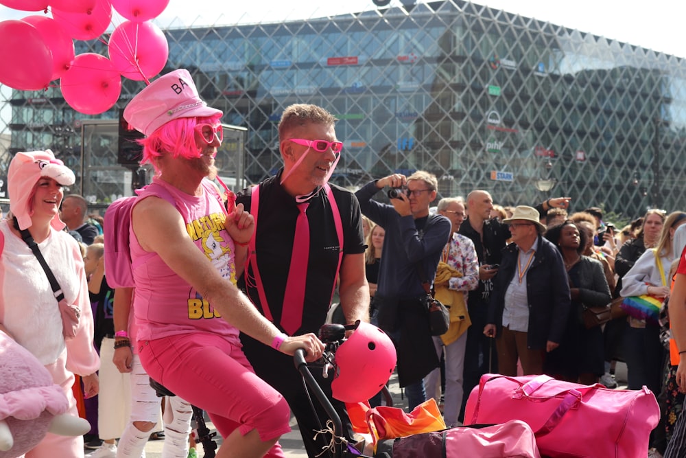 a man riding a bike with pink balloons on the back of it