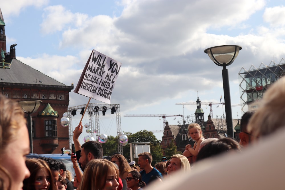 a crowd of people standing around each other holding signs