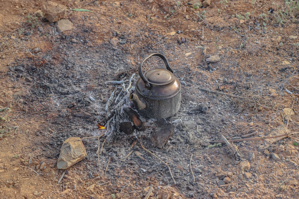 a kettle sitting on top of a pile of dirt