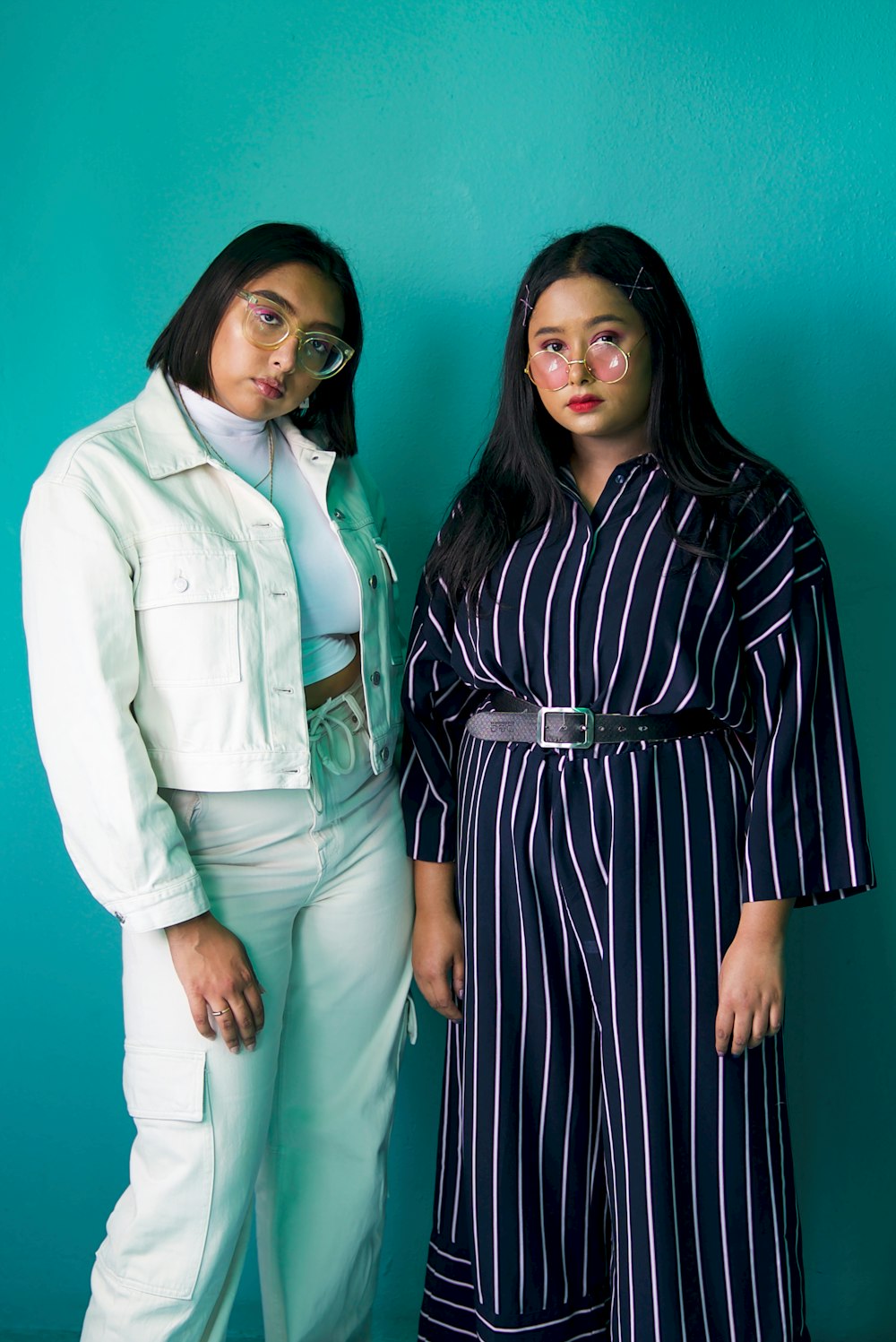 two women standing next to each other in front of a blue wall