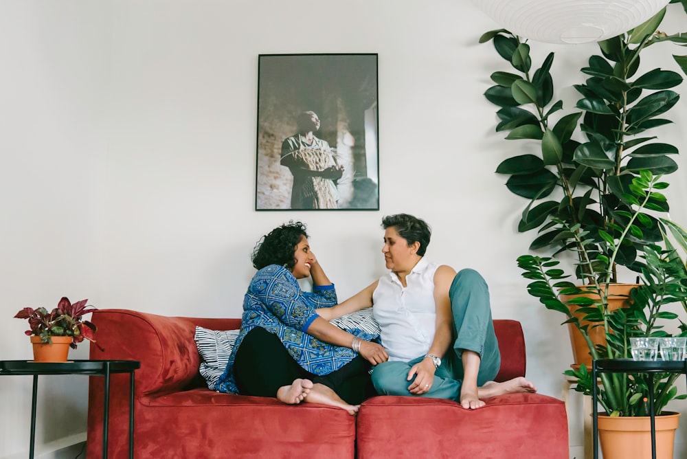 a man and a woman sitting on a red couch