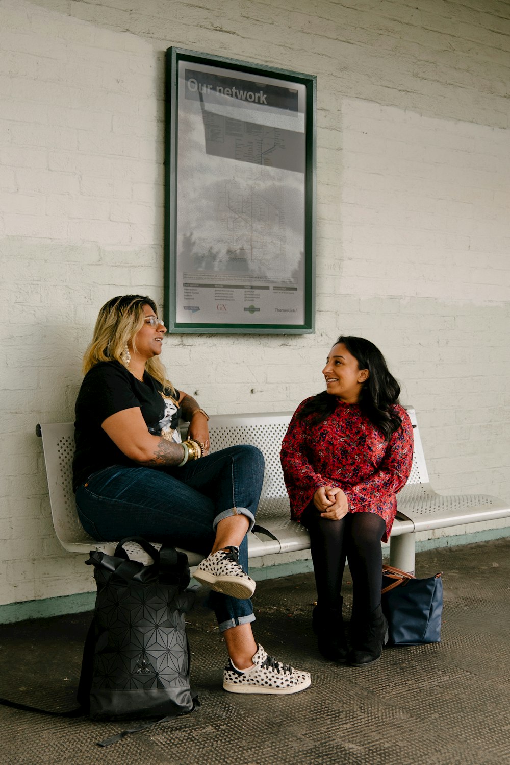 two women sitting on a bench talking to each other