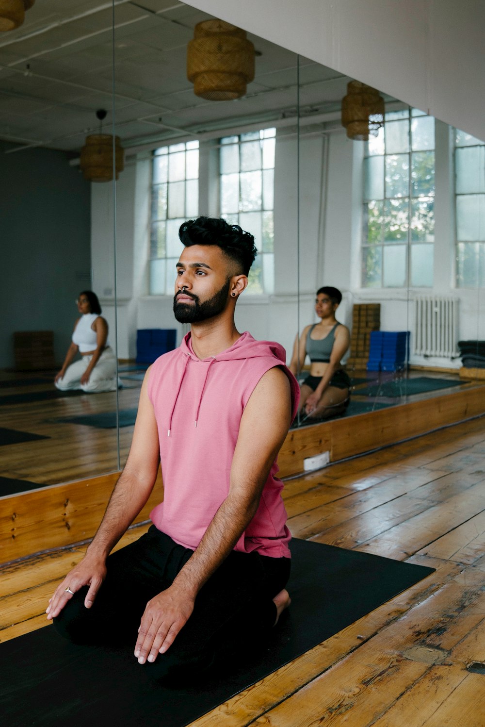 a man sitting on a yoga mat in a gym