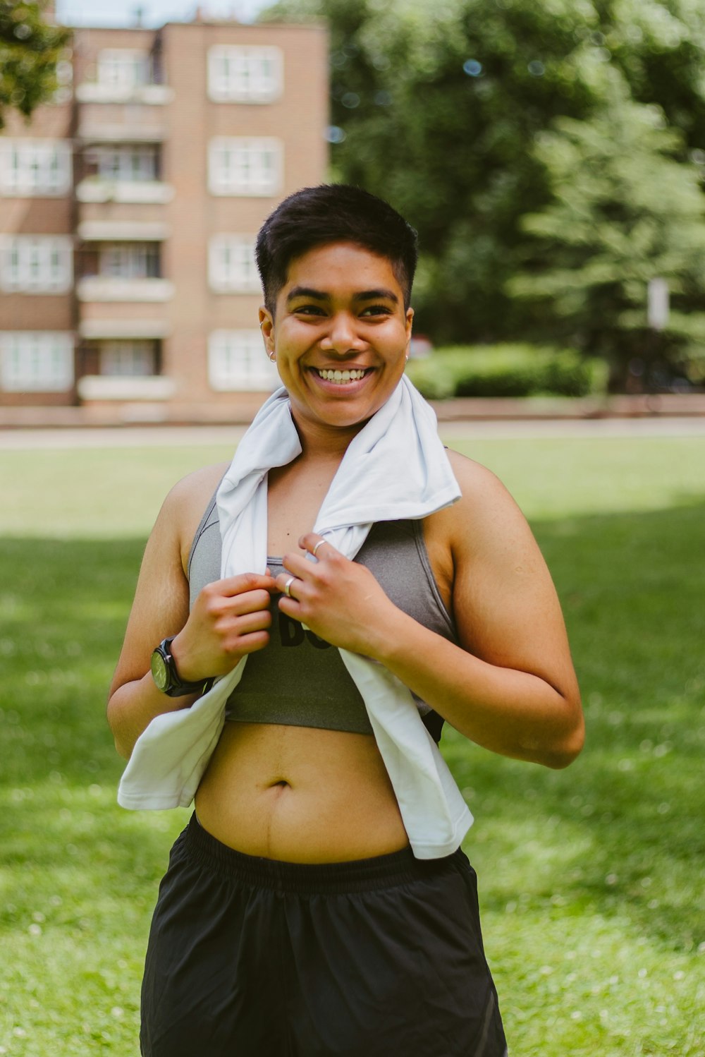 a woman in a sports bra smiling and holding a towel