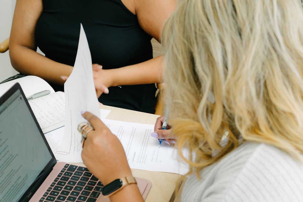 a woman sitting at a table with a laptop and papers