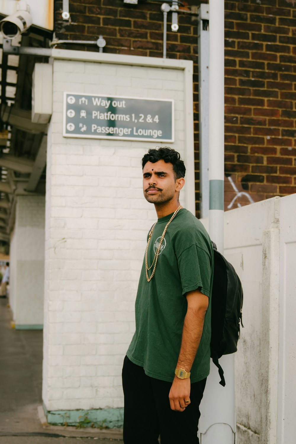 a man in a green shirt standing next to a building