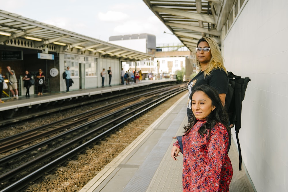 a man and a woman standing next to a train station