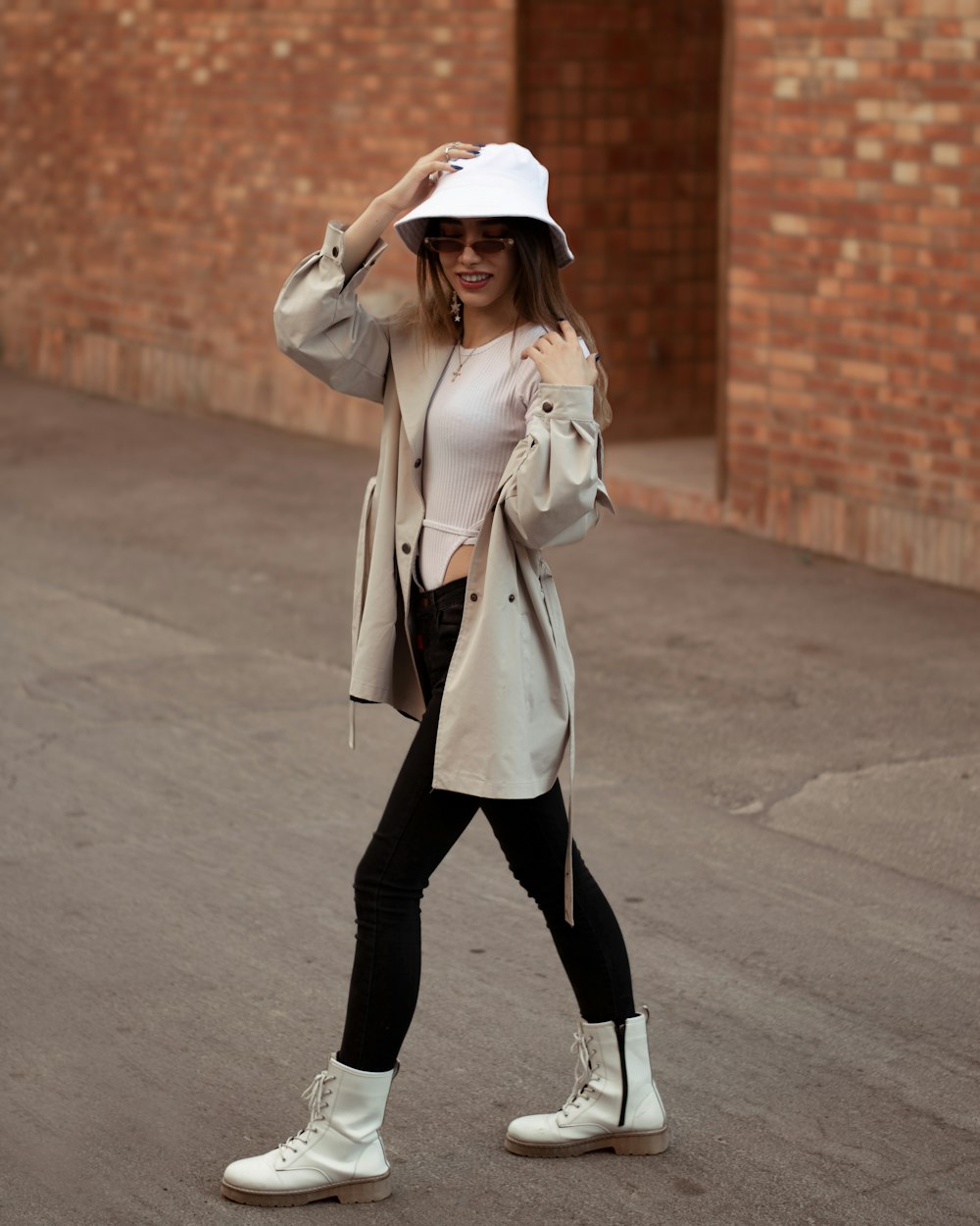 a woman walking down a street wearing a white hat