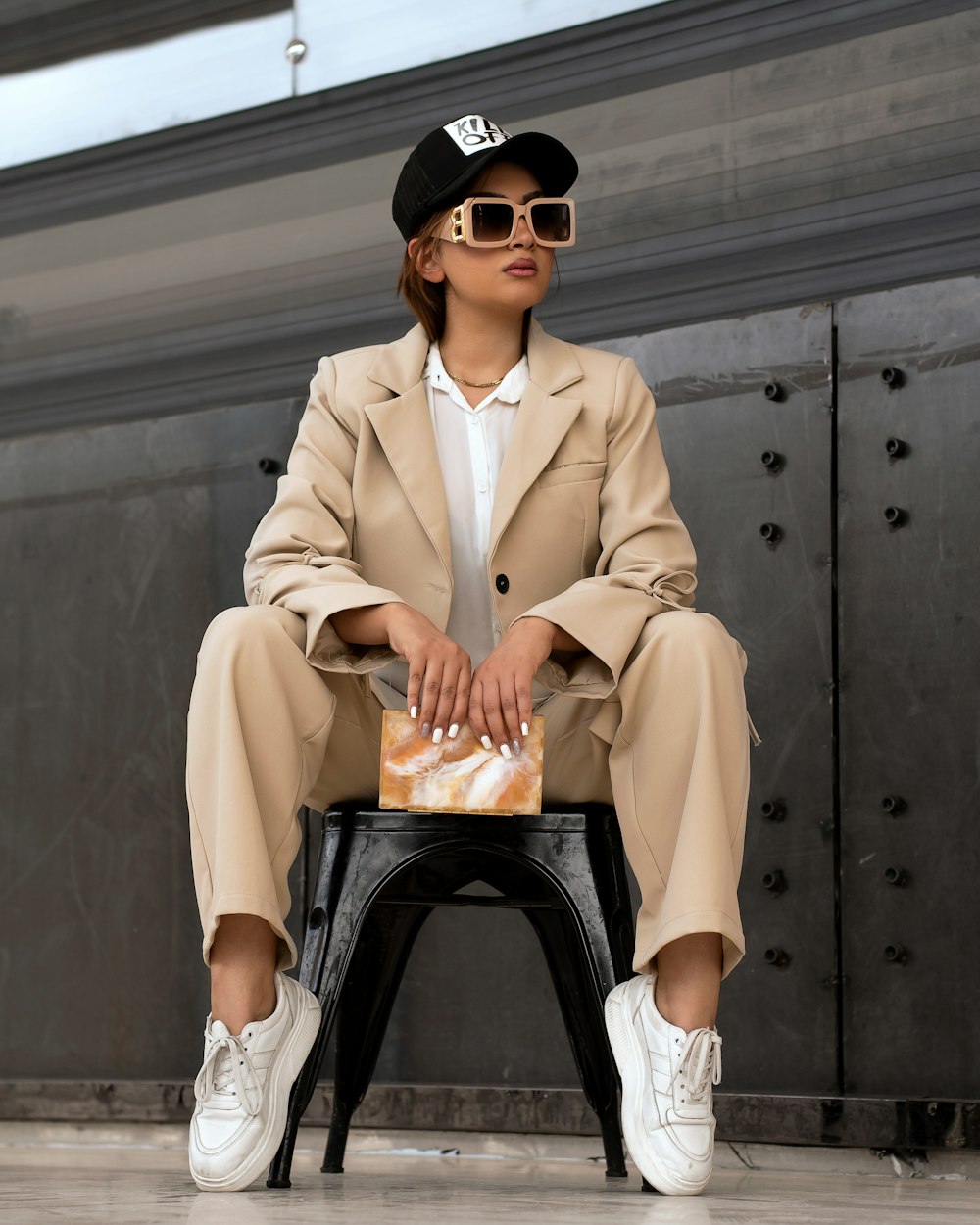 a woman sitting on a chair wearing a hat and sunglasses