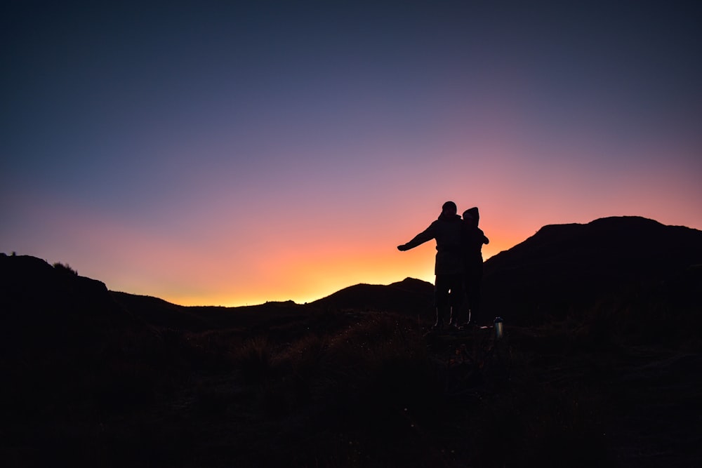 a couple of people standing on top of a hill