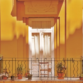 a balcony with potted plants and a wrought iron railing
