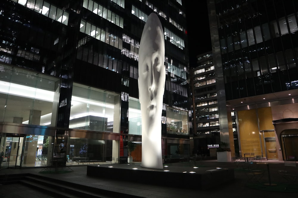 a large white sculpture sitting in front of a tall building