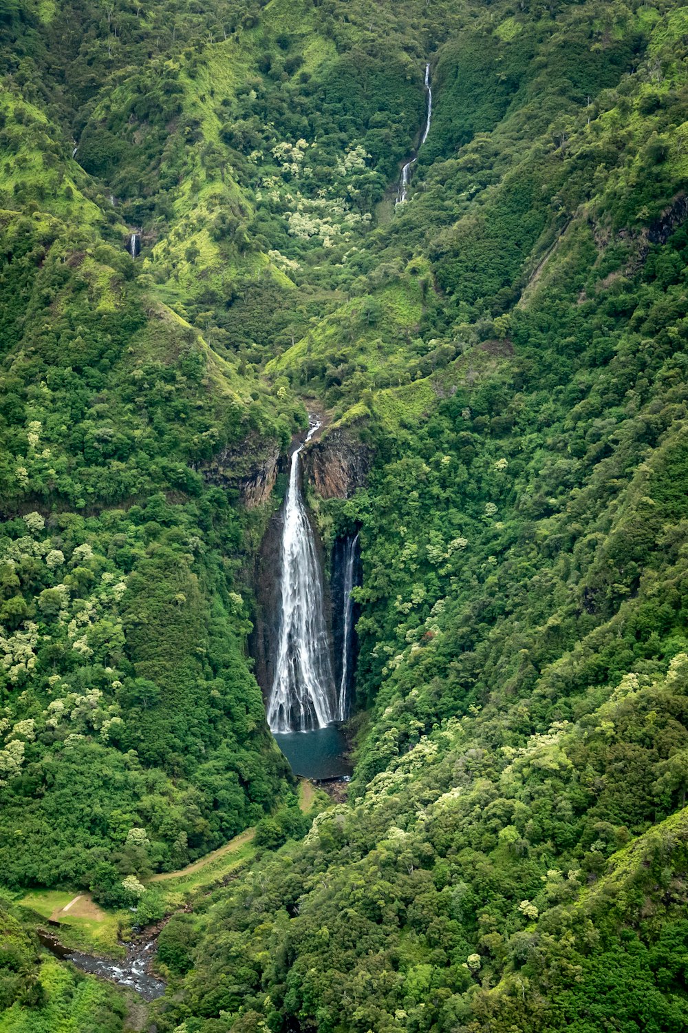 a waterfall in the middle of a lush green valley