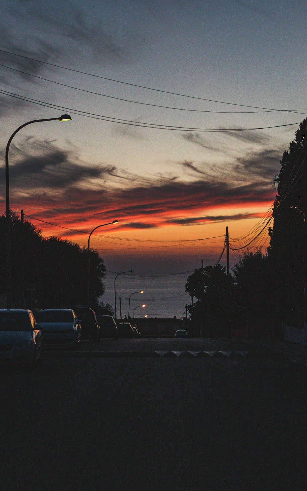 a sunset view of a street with cars parked on the side of the road