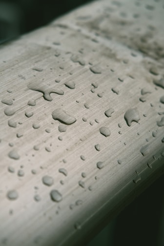 Close-up of a sleek fridge water filter cartridge with droplets of fresh water on its surface.