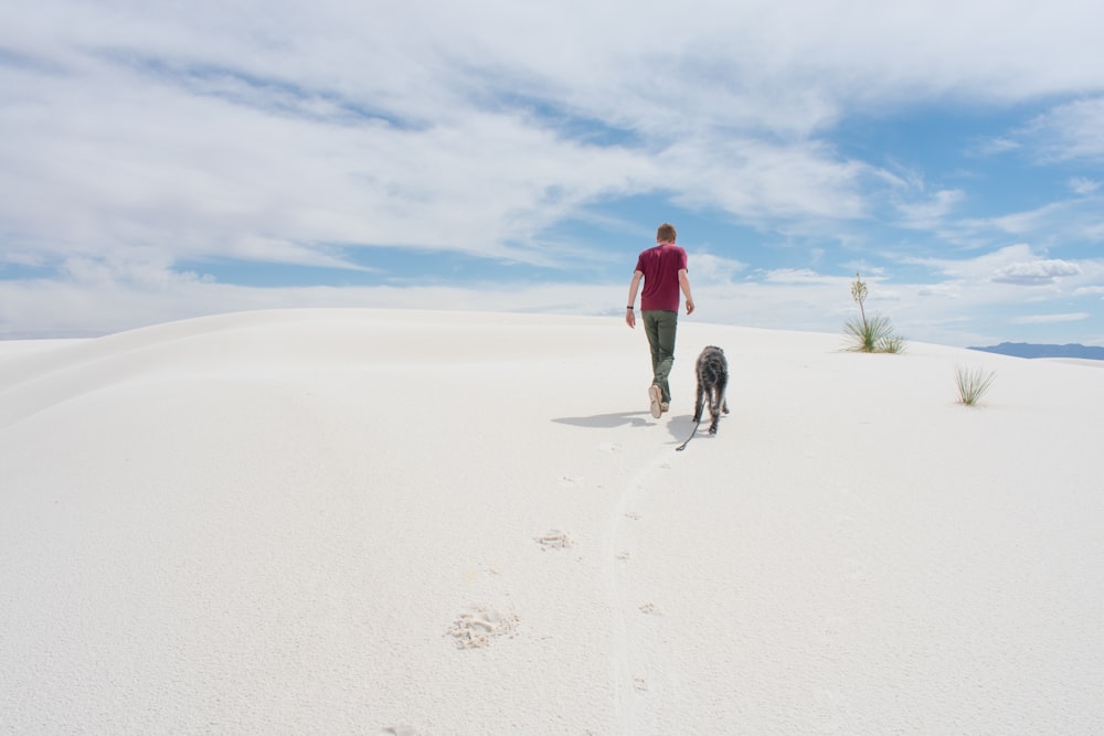 a man and his dog are walking in the sand