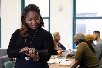a woman standing in front of a table holding a tablet