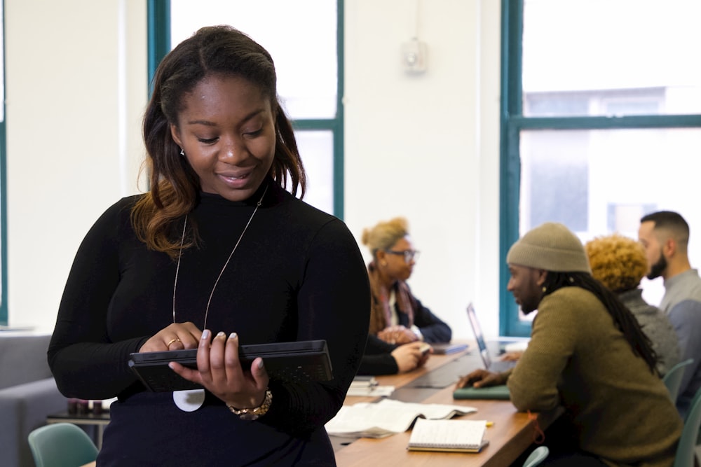 a woman standing in front of a table holding a tablet