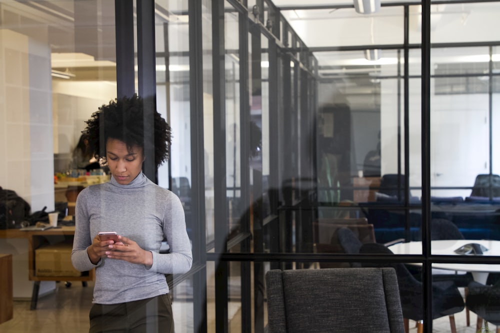 a woman standing in an office looking at her cell phone