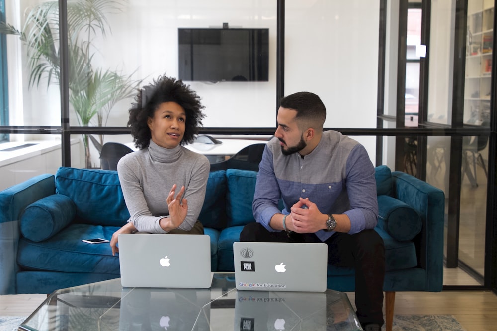 a man and a woman sitting on a couch with their laptops