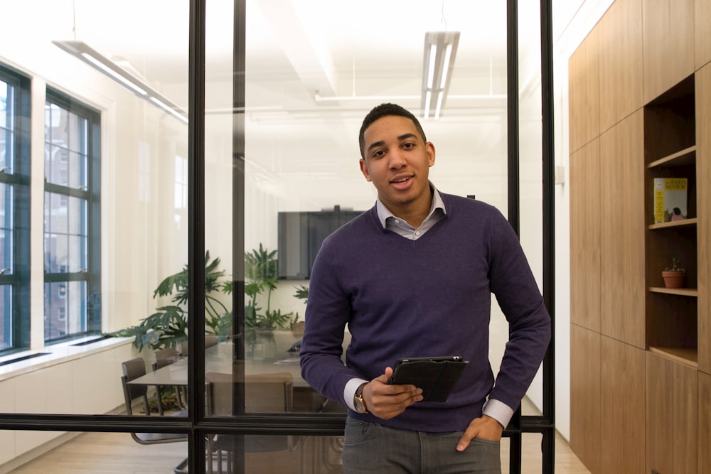 a man standing in an office holding a tablet