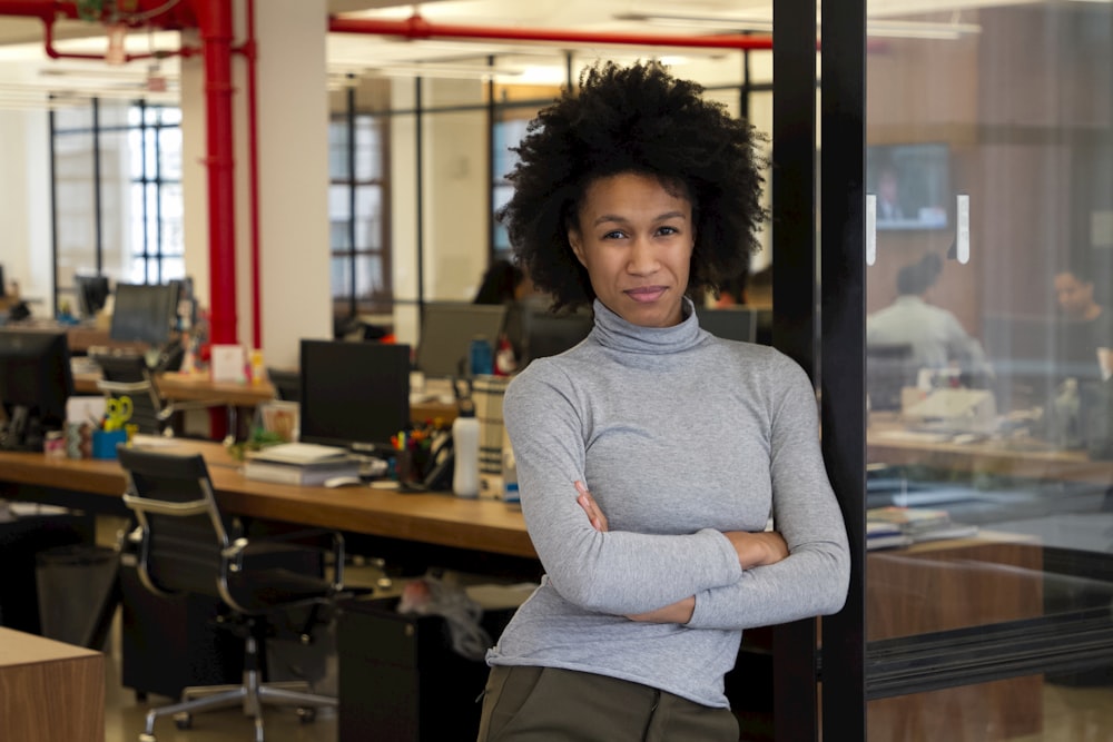 a woman standing in an office with her arms crossed