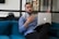 a man sitting on a couch holding a laptop