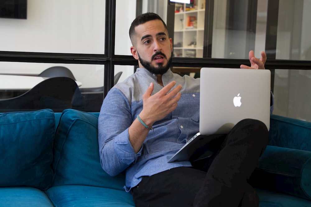 a man sitting on a couch holding a laptop