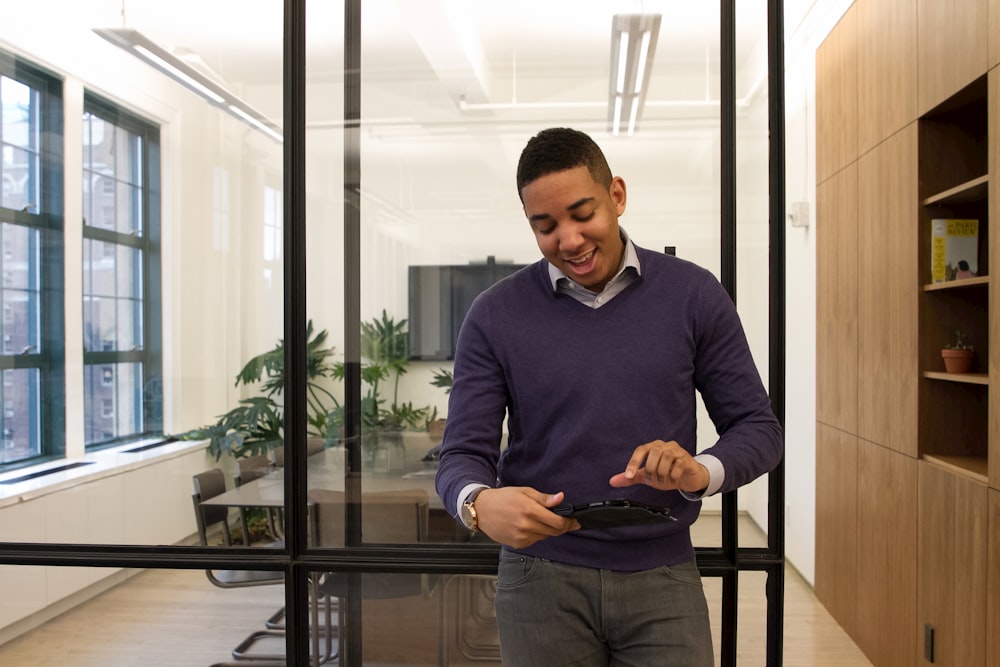 a man standing in an office looking at a cell phone