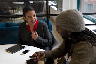 a woman sitting at a table talking to another woman