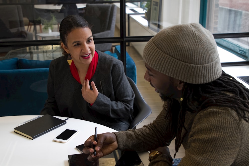 a woman sitting at a table talking to another woman