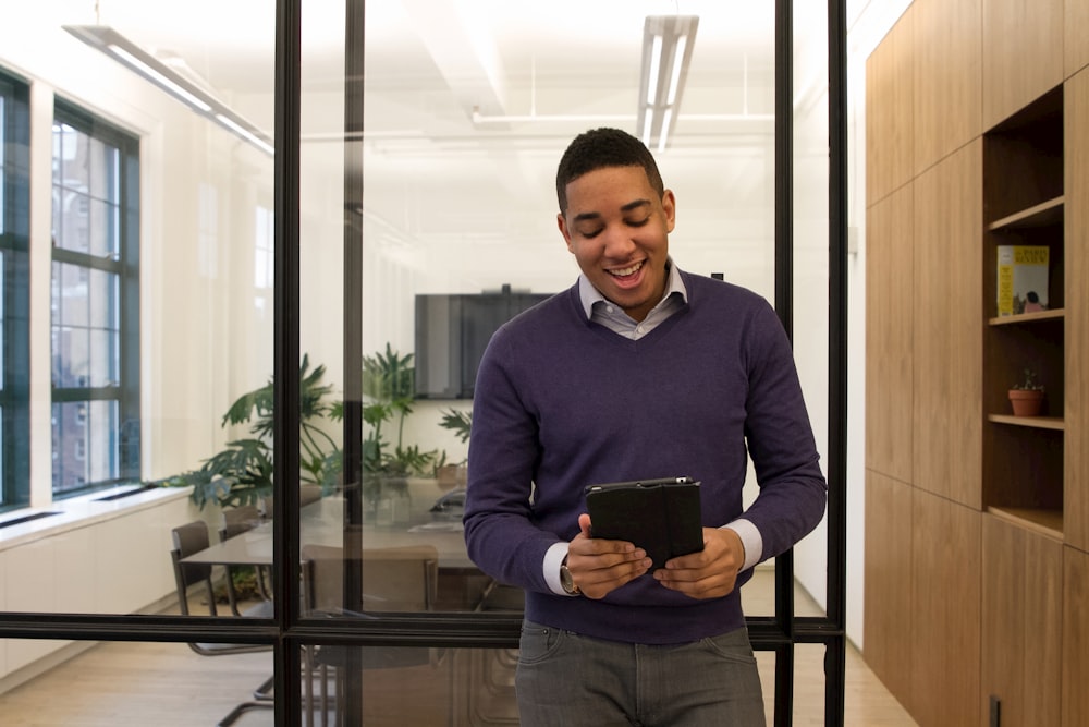 Ein Mann, der in einem Büro steht und auf ein Tablet schaut