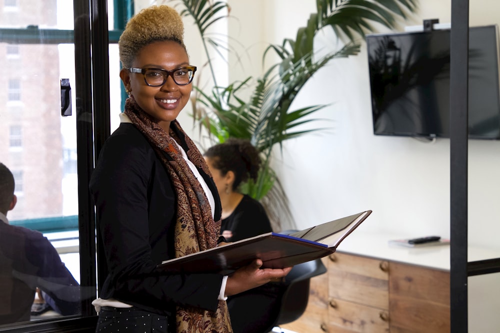 a woman standing in an office holding a binder