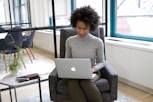 a woman sitting in a chair using a laptop computer