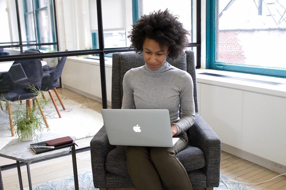 a woman sitting in a chair using a laptop computer