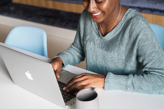 a woman sitting at a table using a laptop computer