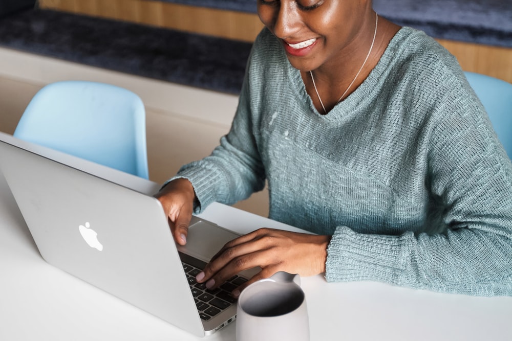 a woman sitting at a table using a laptop computer