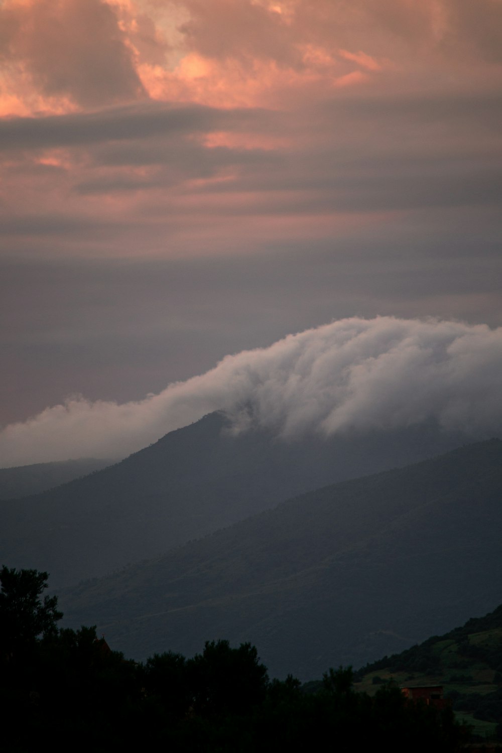 a mountain covered in clouds at sunset