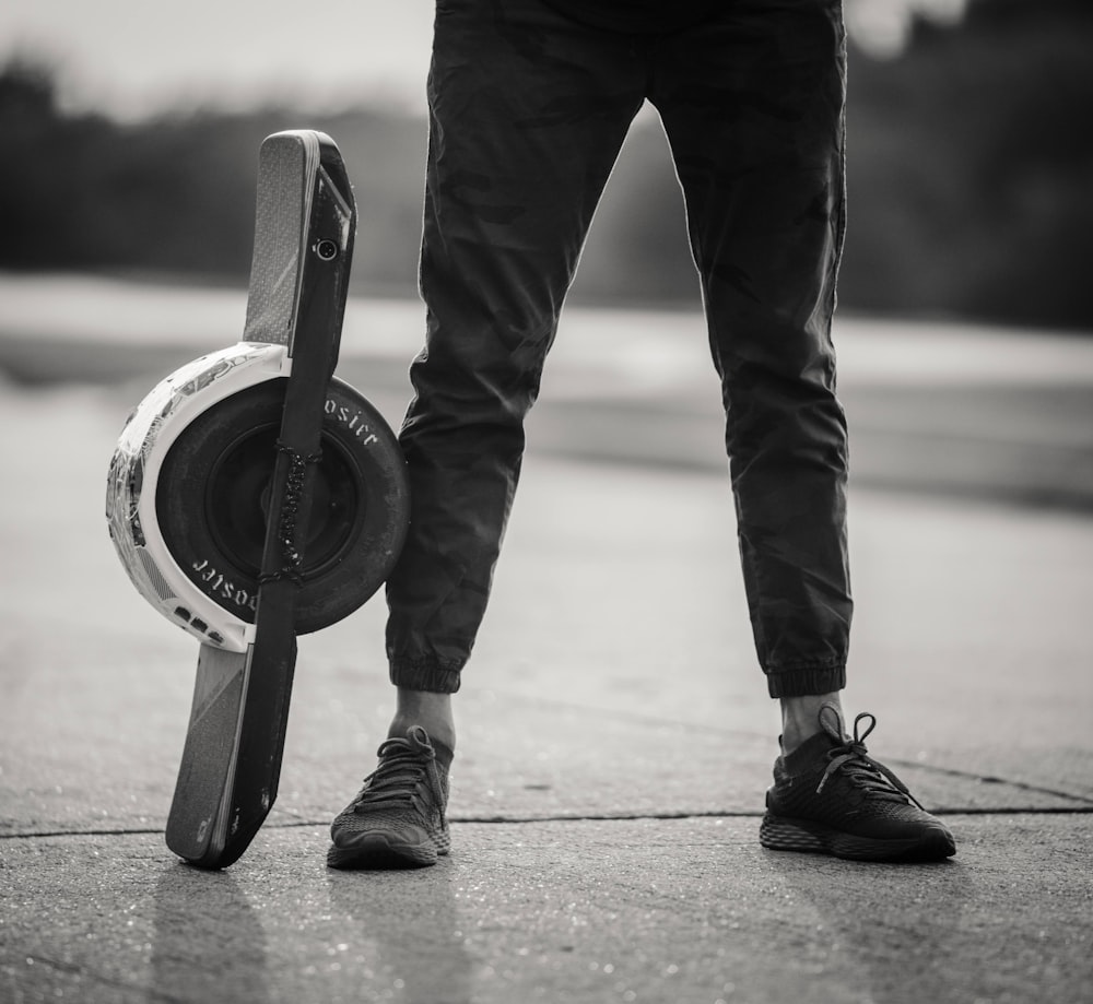 a person standing on a sidewalk holding a skateboard