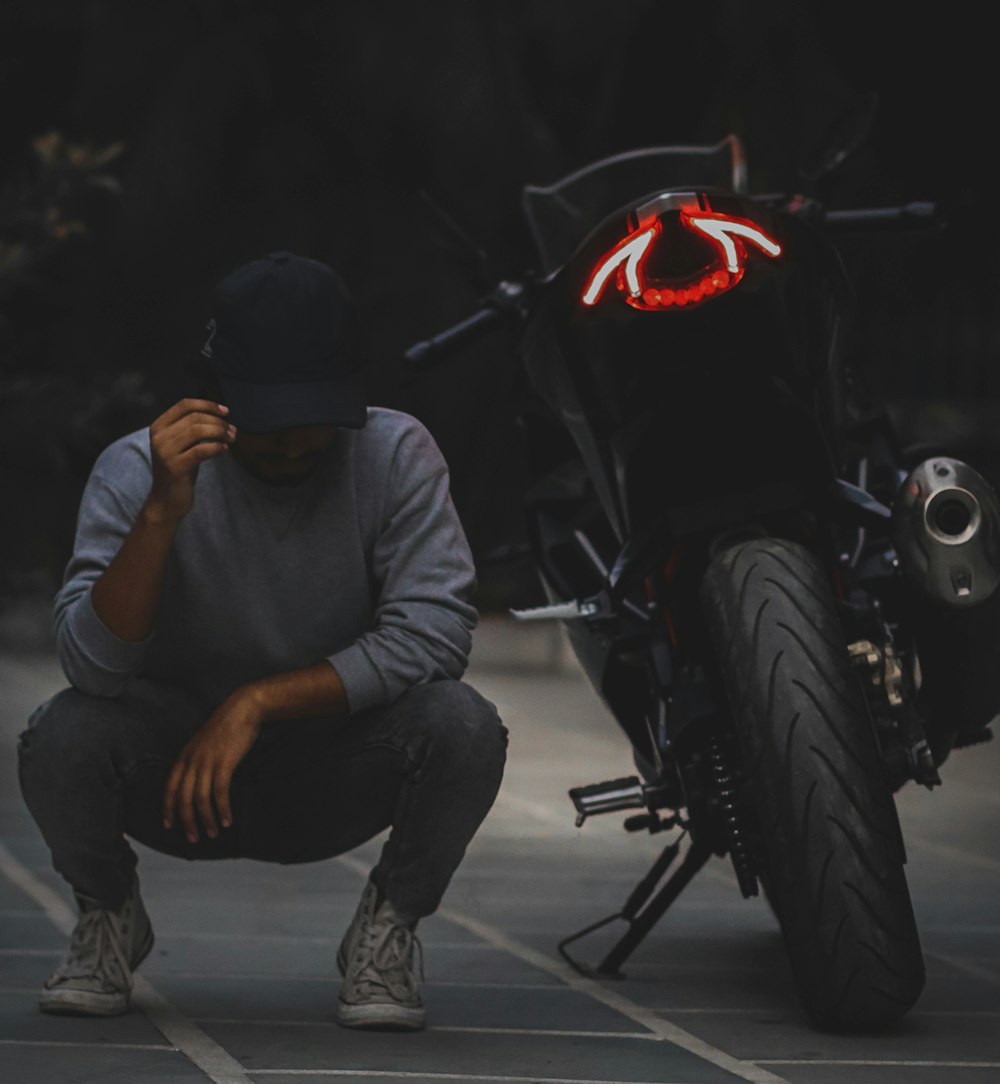 a man kneeling down next to a motorcycle