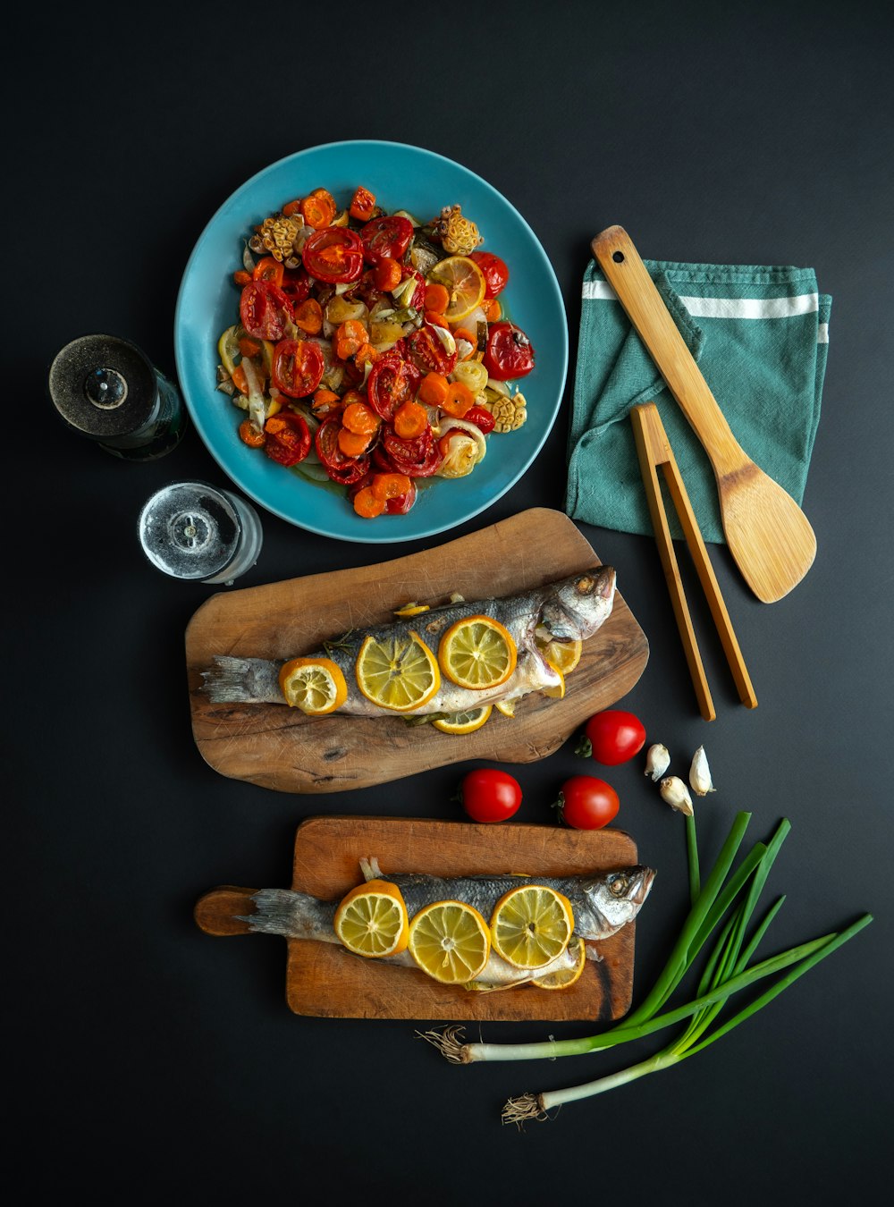a plate of fish with lemons and tomatoes