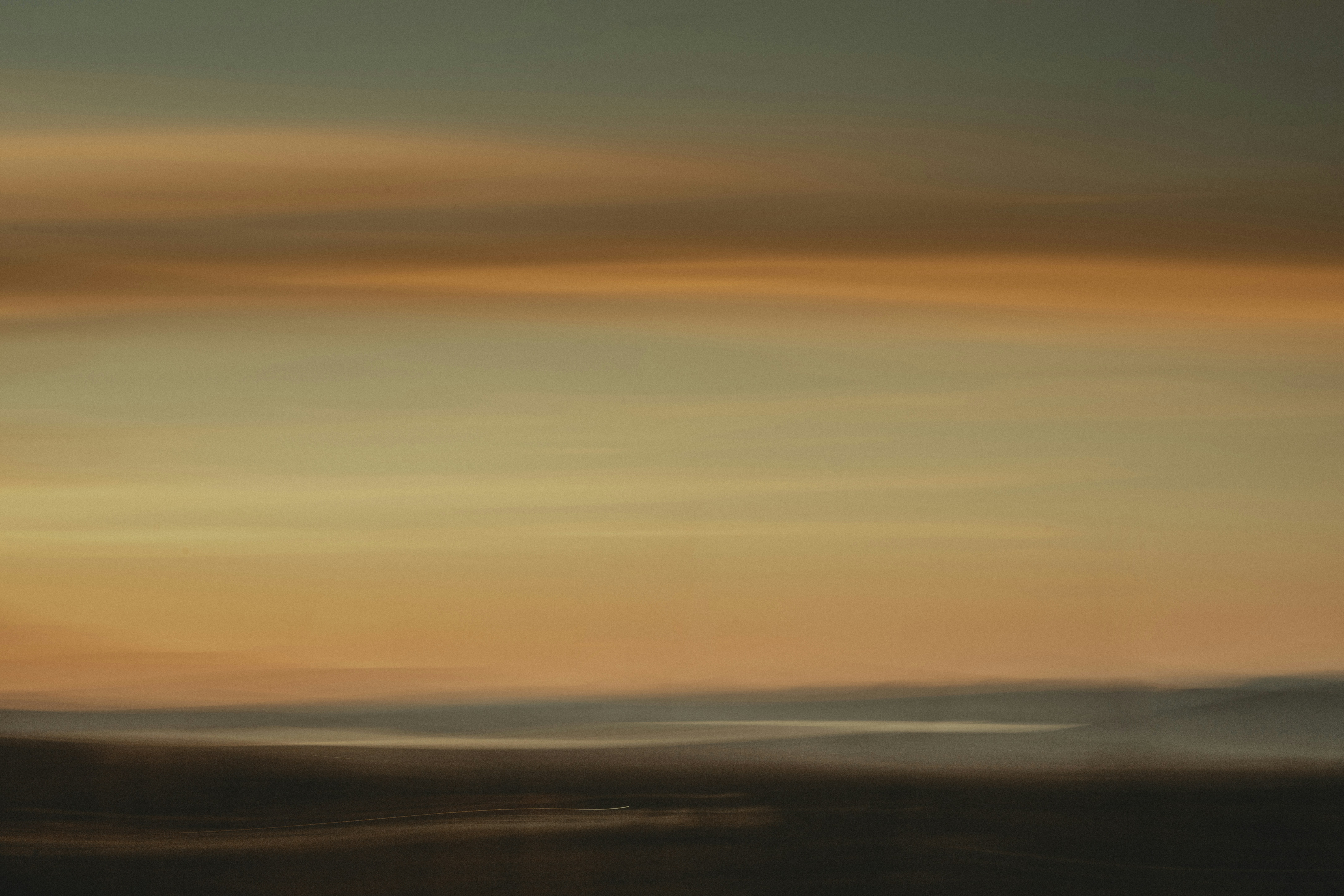 a blurry photo of a sunset with a plane flying in the sky