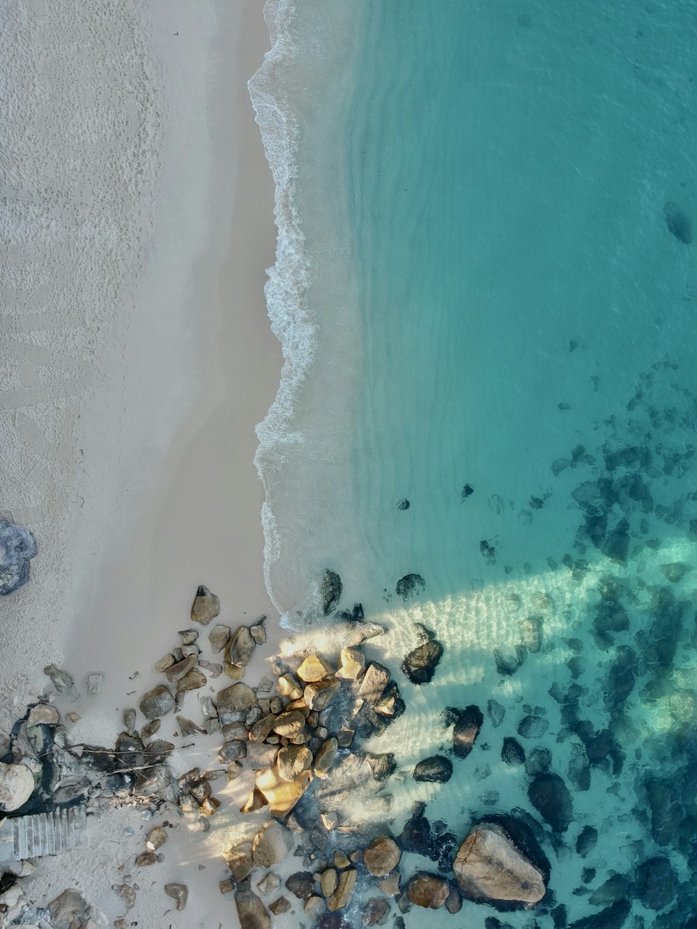 a bird's eye view of a beach with rocks and water