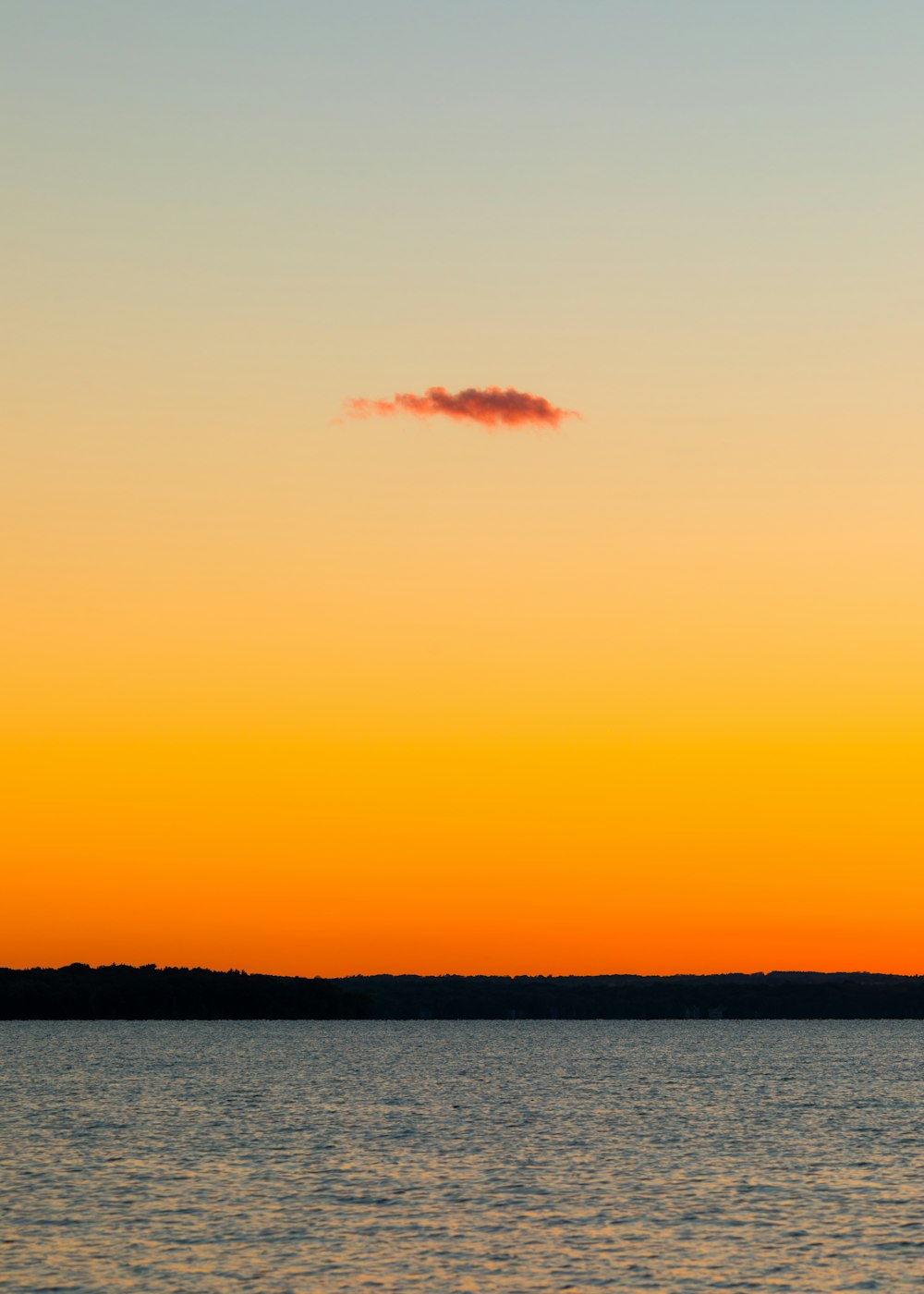 um avião voando sobre um corpo de água ao pôr do sol