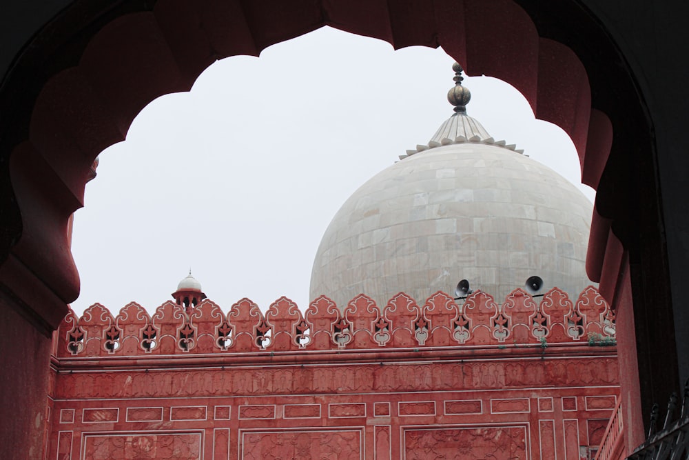 a large white dome sitting above a red wall