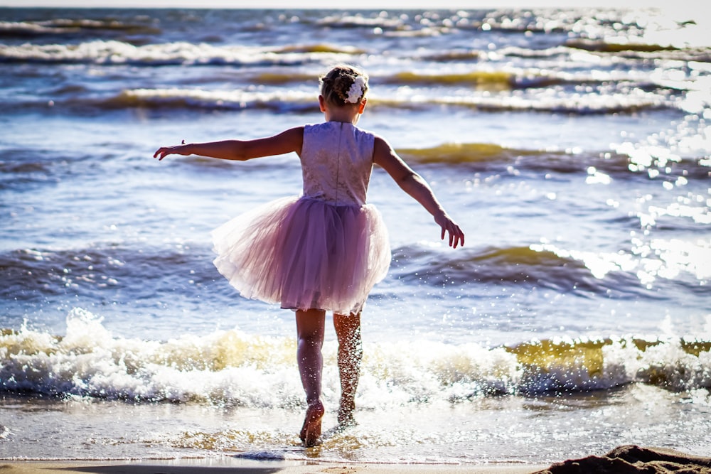 a little girl in a tutu on the beach