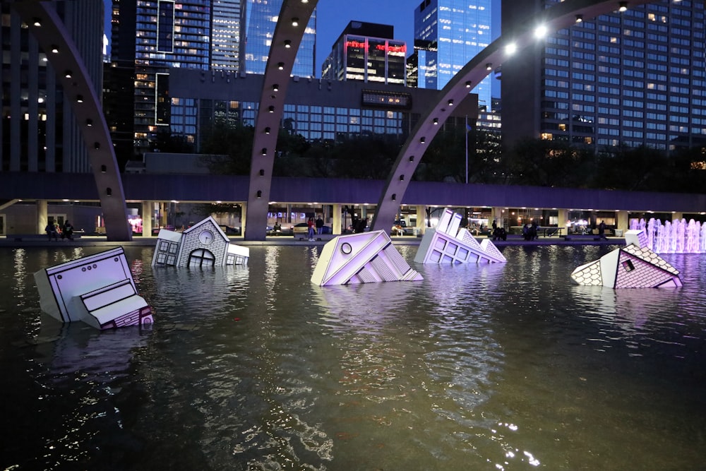 a group of paper houses floating on top of a body of water