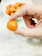 Close-up of a hand holding a bite-size tropical dessert with vibrant colors and a rustic wooden background.