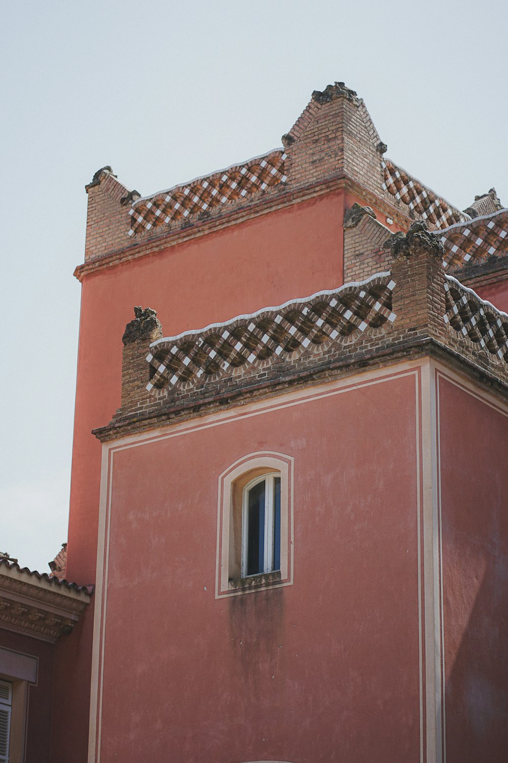 um edifício vermelho alto com um relógio ao seu lado